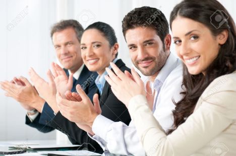 8590040-satisfied-proud-business-team-clapping-hands-and-looking-at-camera-in-a-modern-office-stock-photo